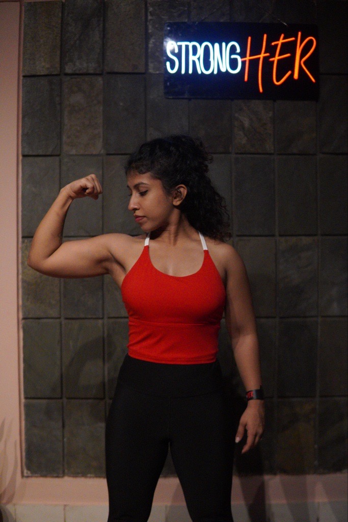 After training, flexing in front of the StrongHer sign